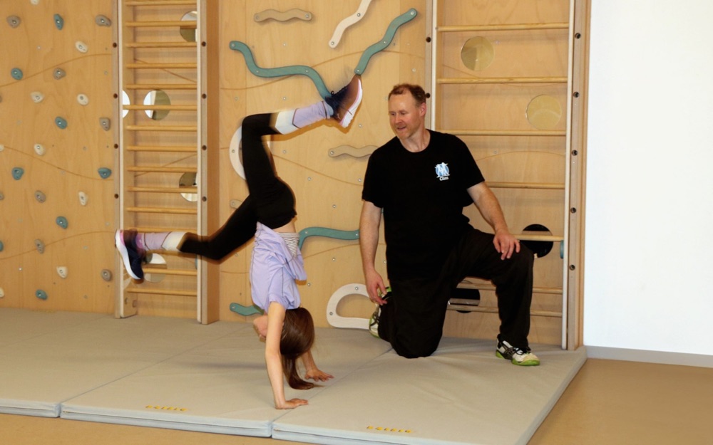 Claas sichert ein Kind beim Handstand